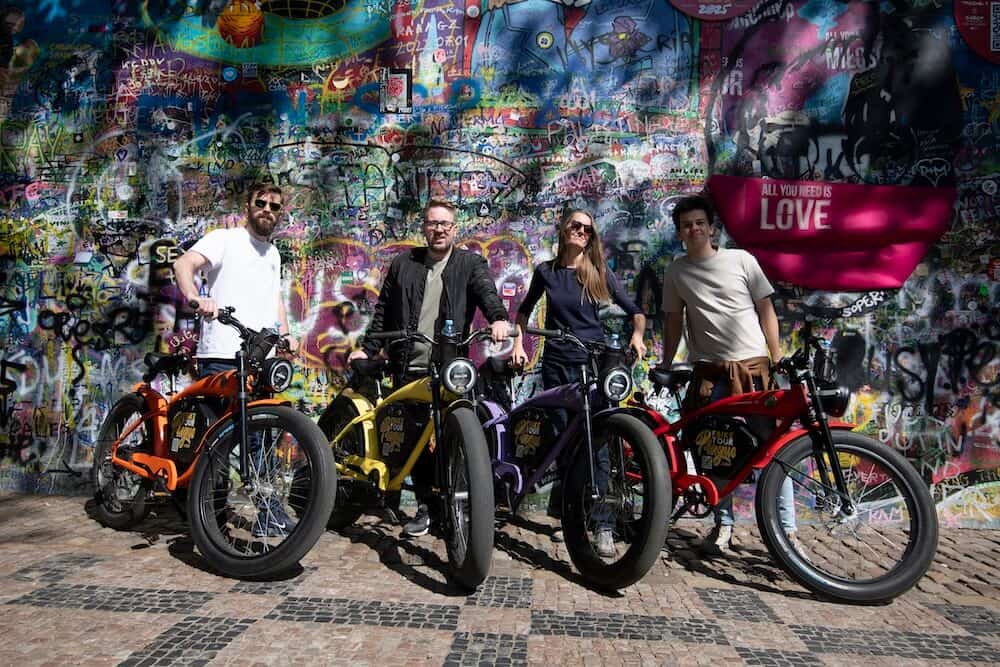 Group of riders with café-racer e-bikes at the Lennon Wall in Prague